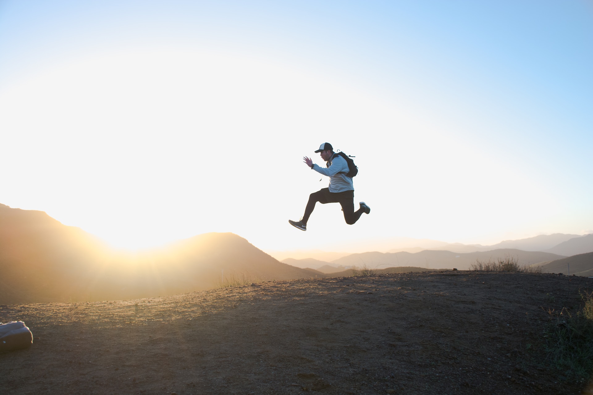 man jumping with the sunset in the background with positive messages