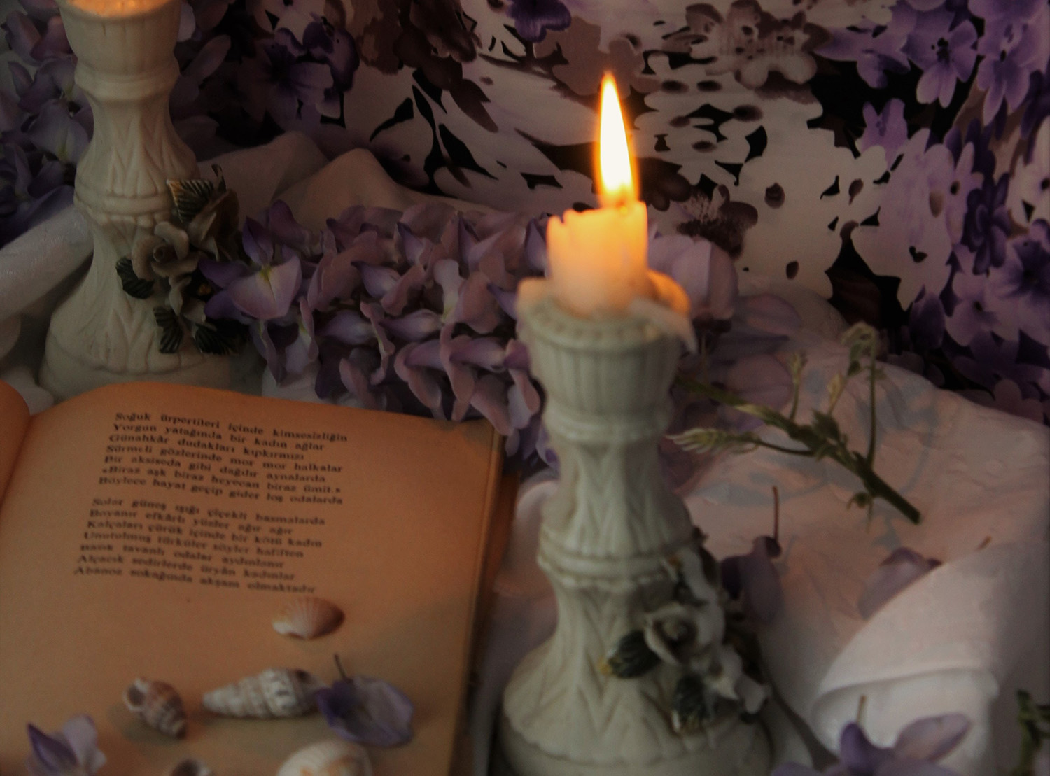lighted candle next to book with good night my love messages and floral wallpaper