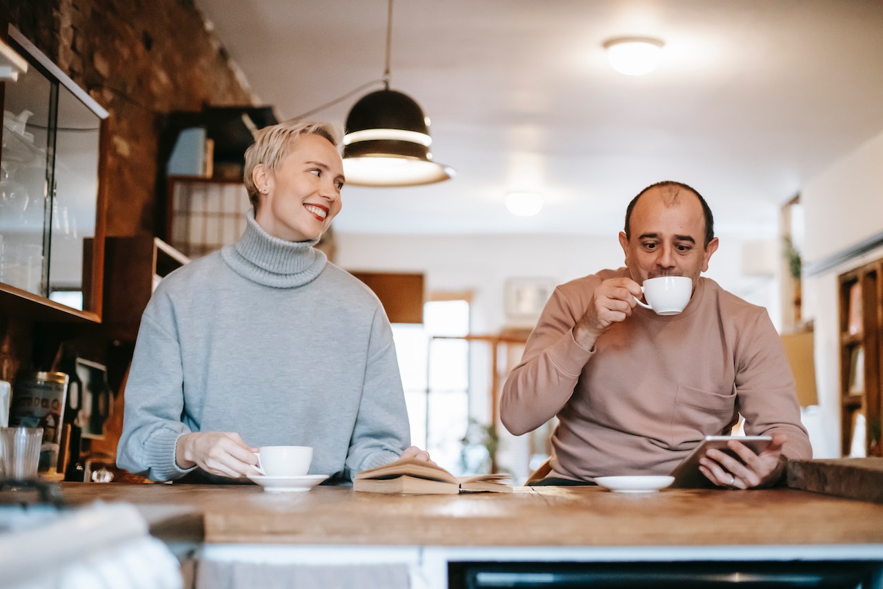couple having coffee in the morning while the woman says good morning for him
