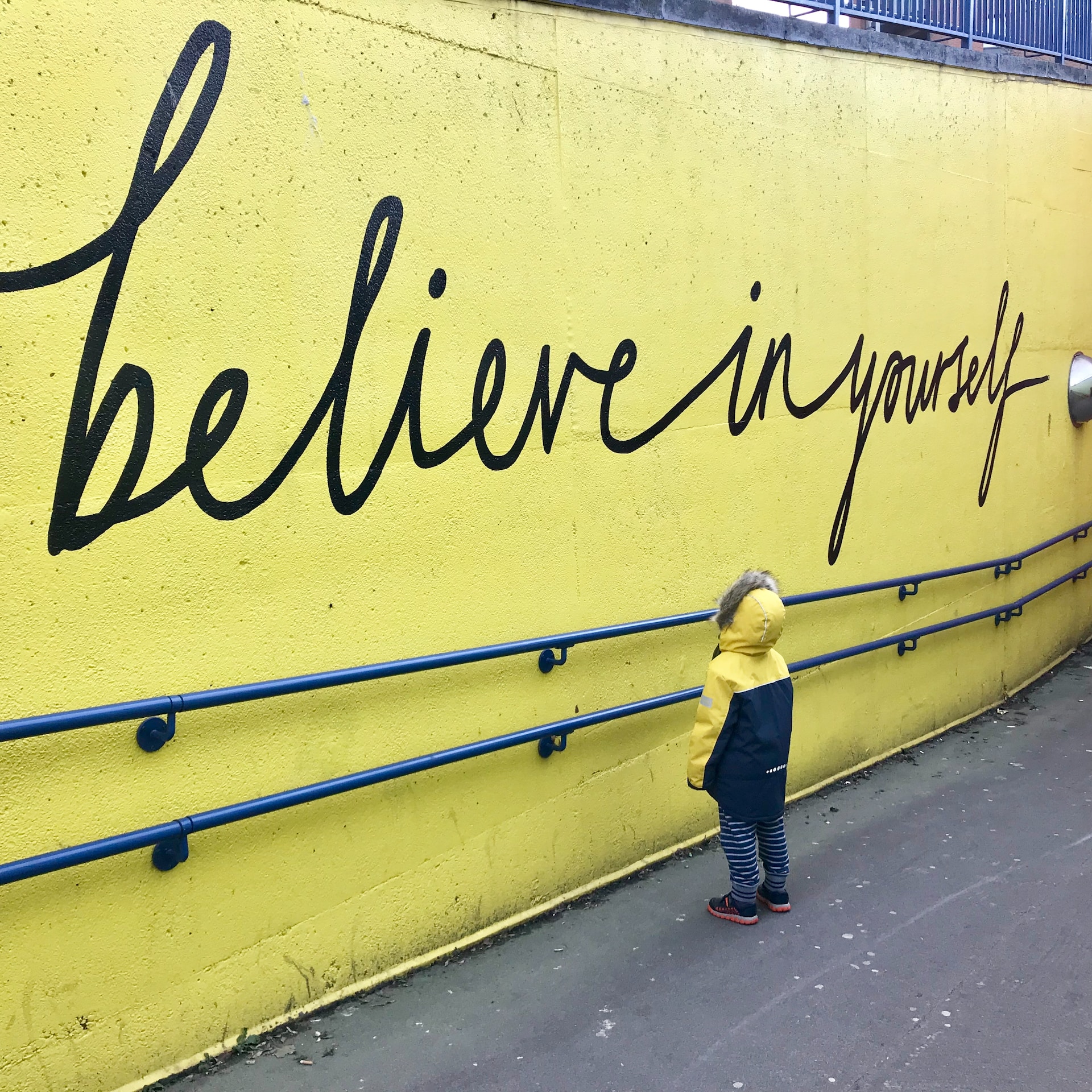 little boy reading positive message believe in yourself in the wall