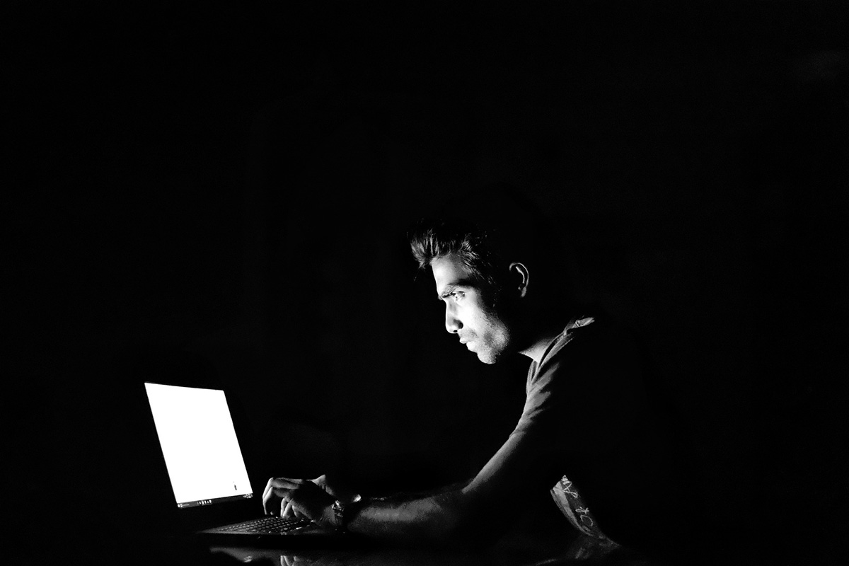 man using a laptop in the dark 