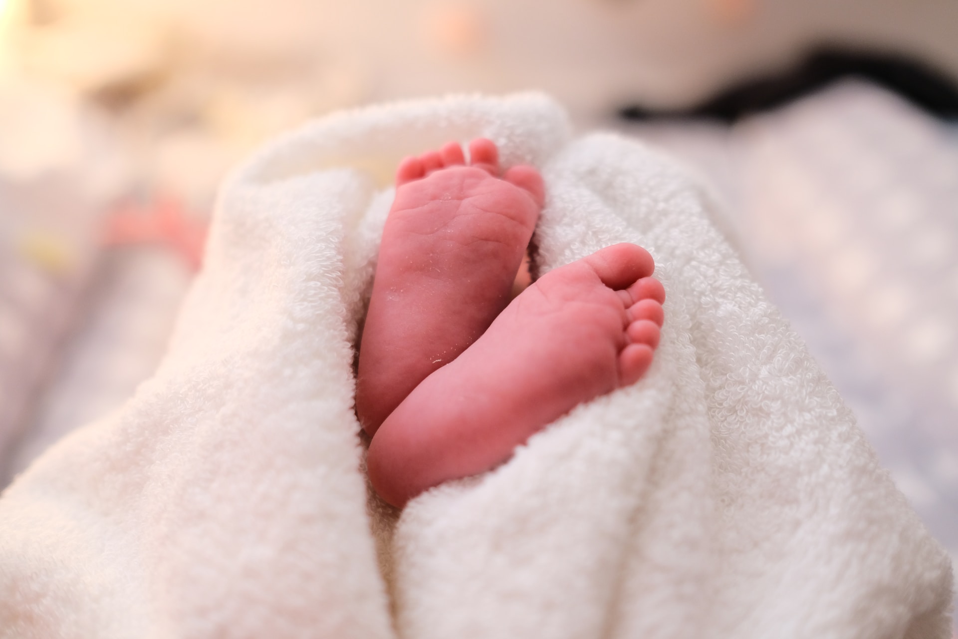 close into a newborn's feet covered by a white blanket happy mother's day for the first time