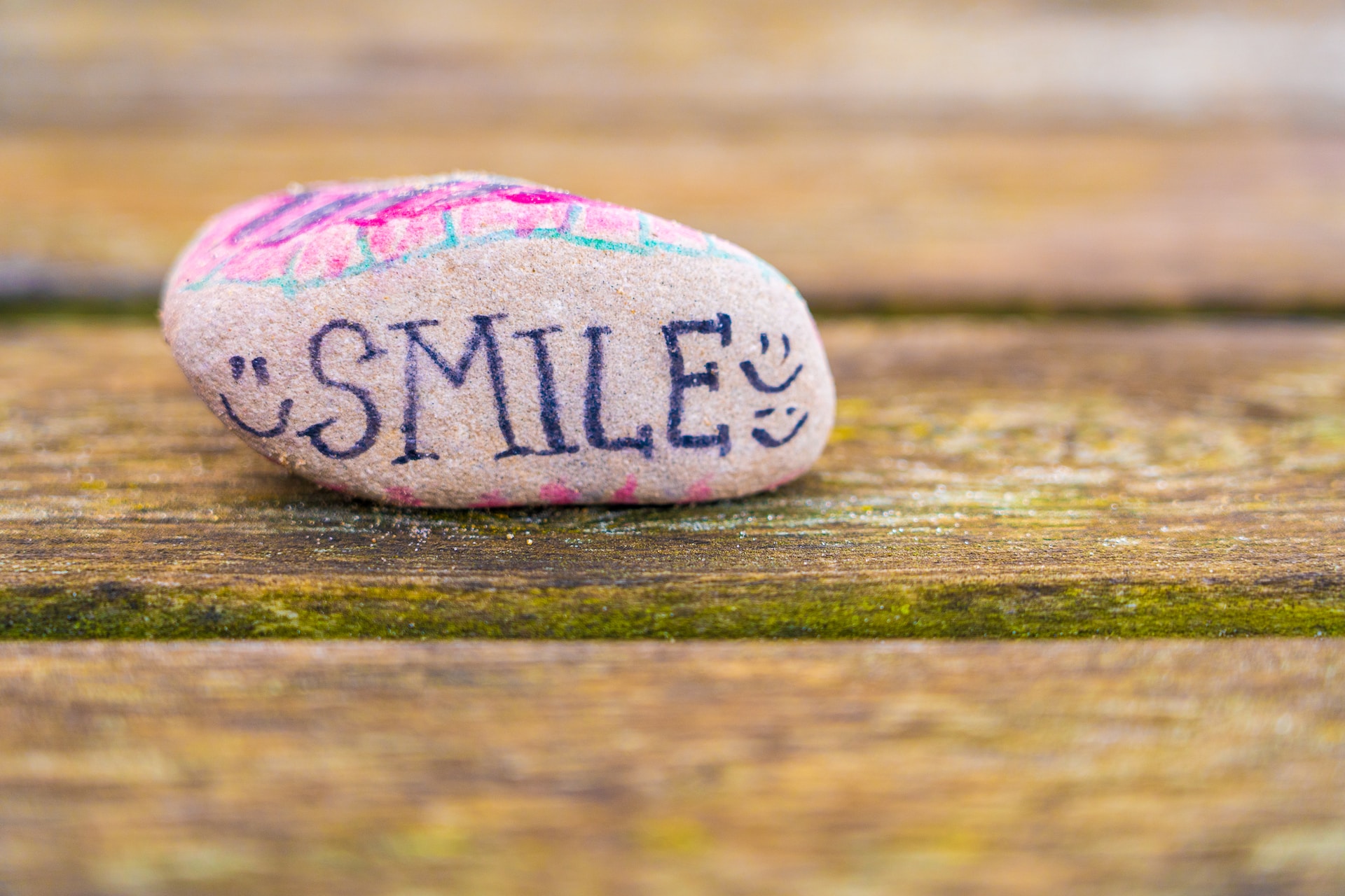 pink rock with positive message smile written with markers
