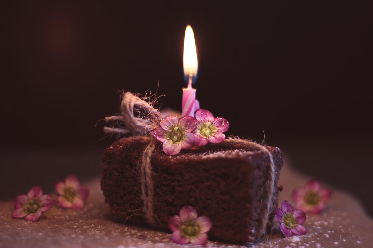 small chocolate cake with pink lighted candled on top to send happy birthday girlfriend messages