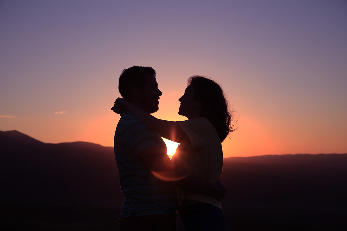 people hugging in love in a sunset background