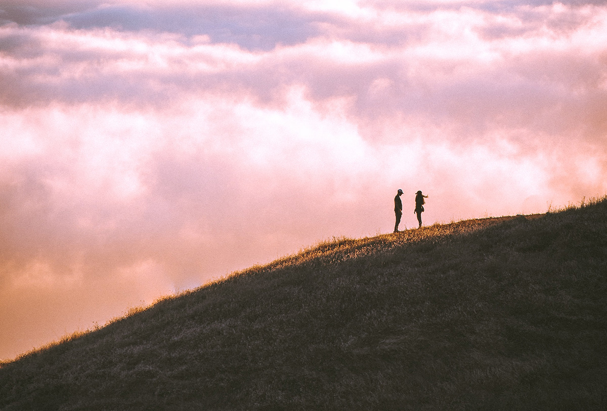 Two people standing in a mountain hill having a romantic experience together