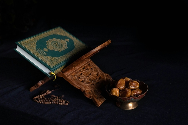 quran in a wooden platform for how to say happy ramadan with dried fruits by its side