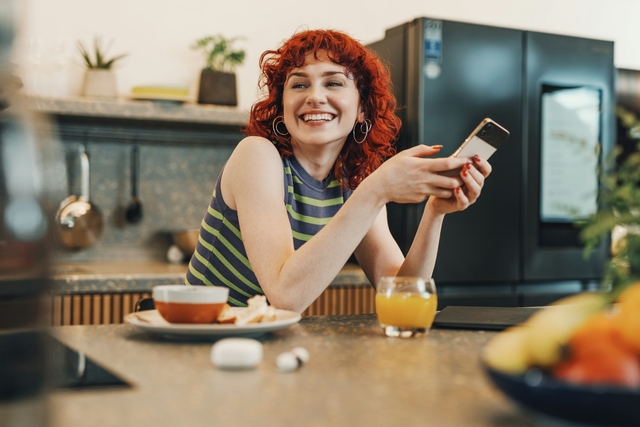 woman smiling with phone in her hands receiving an e-greeting card online