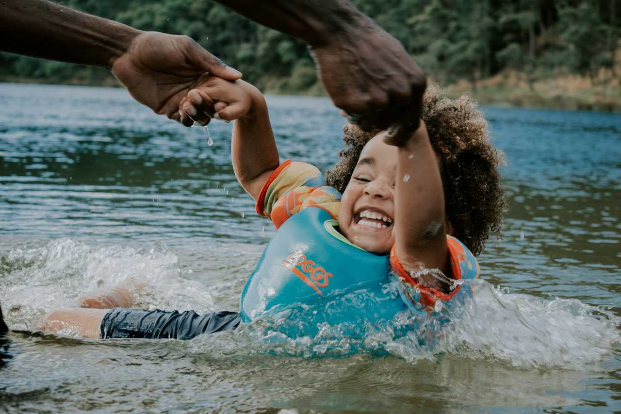 young daughter playing in a lake with her father wearing a kid's life vest for daughter quotes