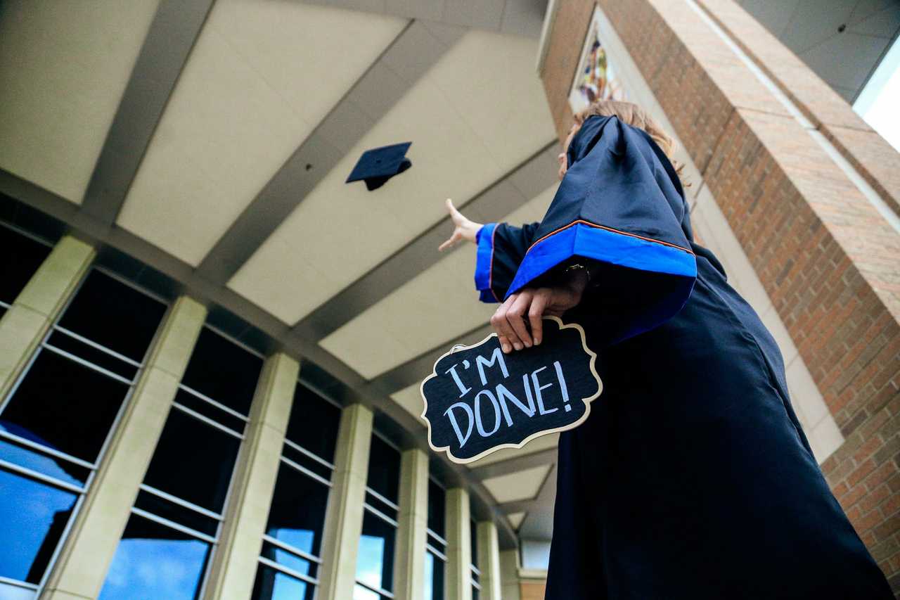 Graduating student throwing the hat up holding a graduation message saying I'm Done