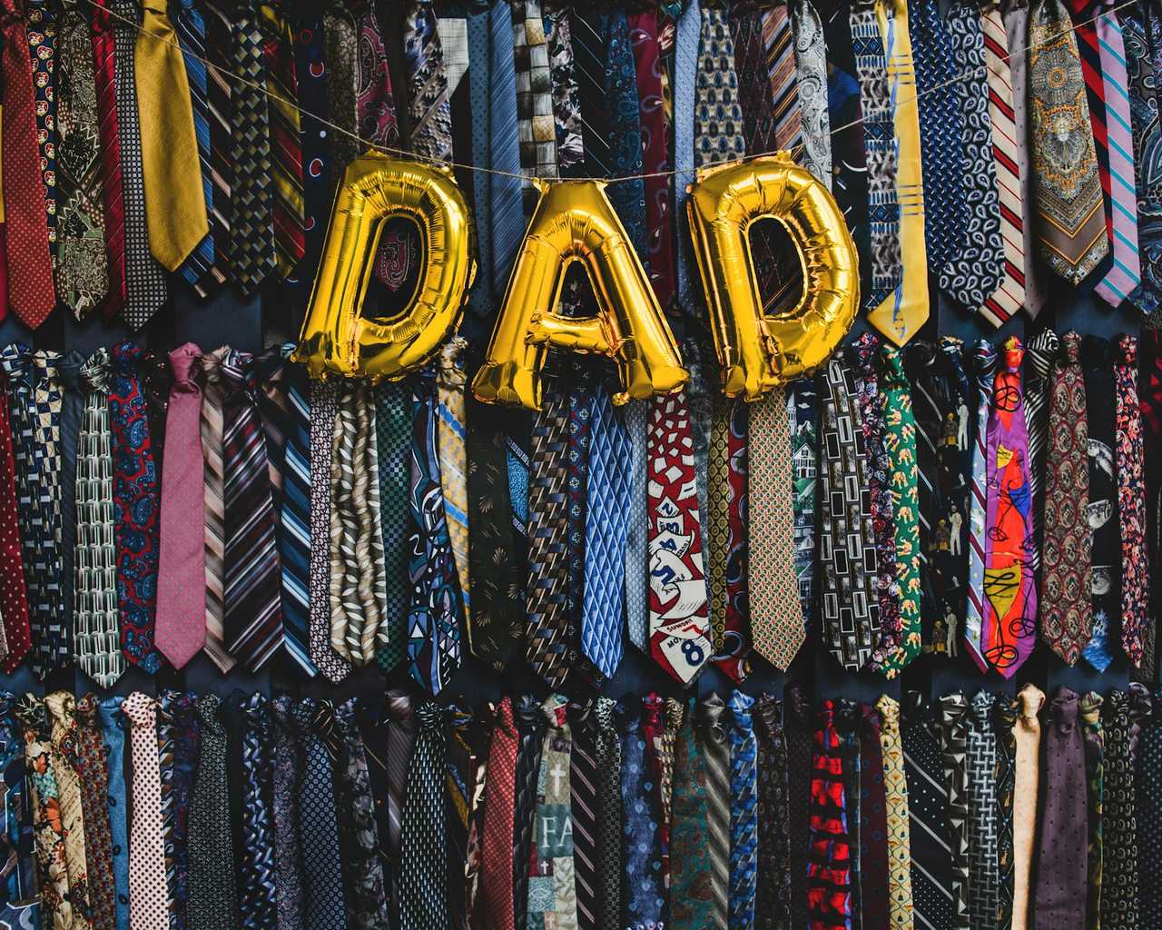 dad written with balloons in front of a wall of ties for father's day quotes
