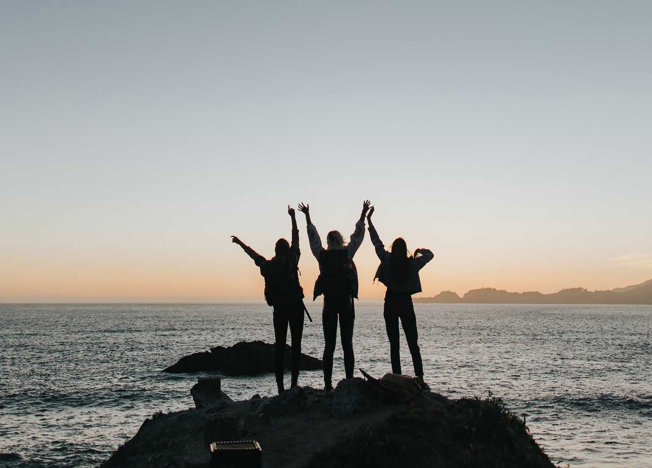 three people cheering by the sea getting ai congratulation messages