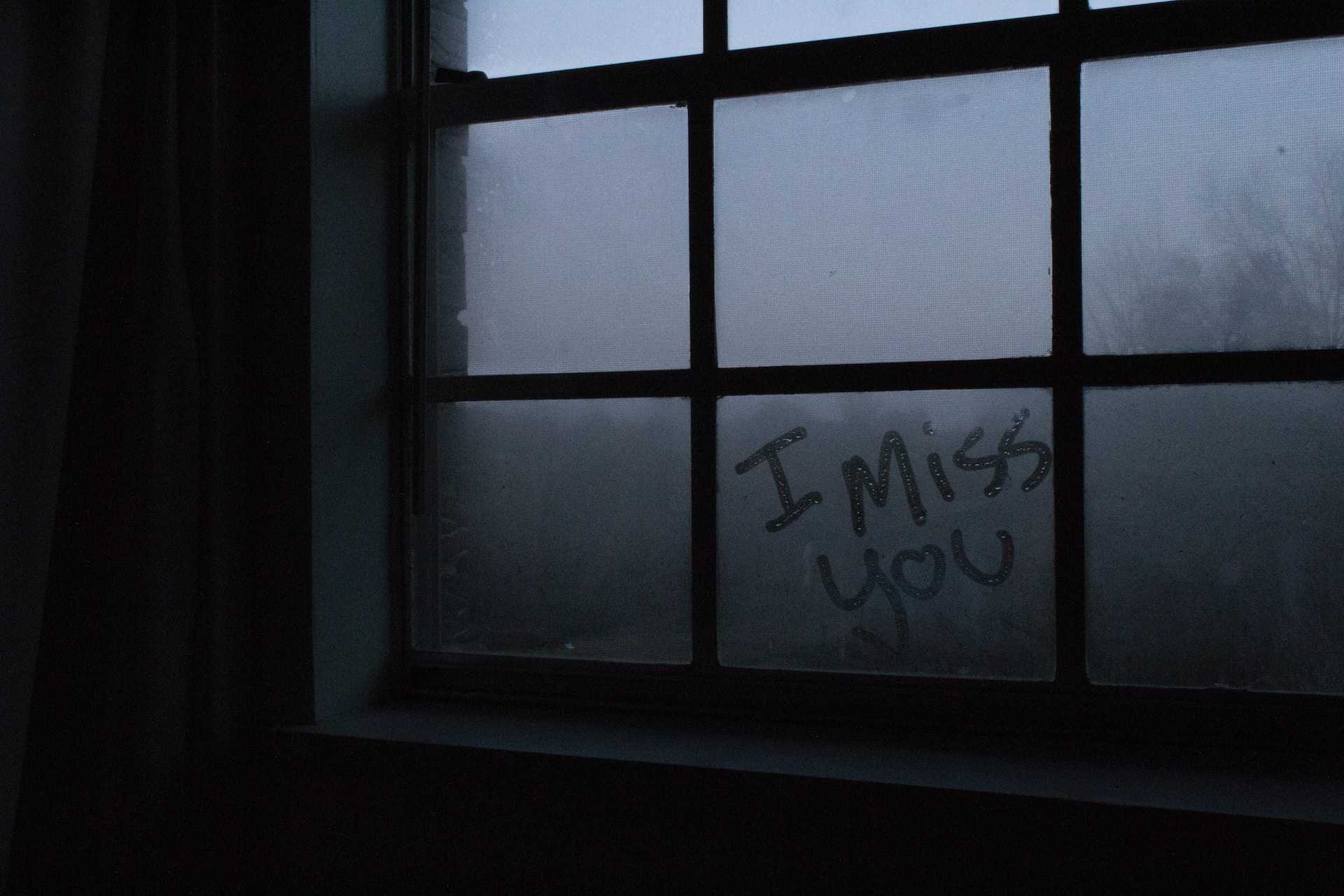 i miss you wrote in a wet glass window in a dark room