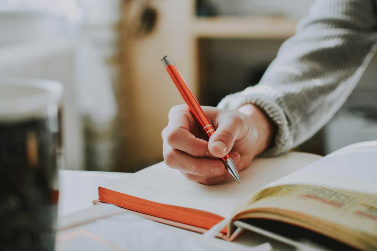 detail of a hand writing a greeting card test in a notebook