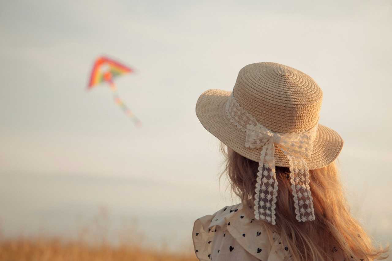 daughter wearing a hat looking at a kite in the sky