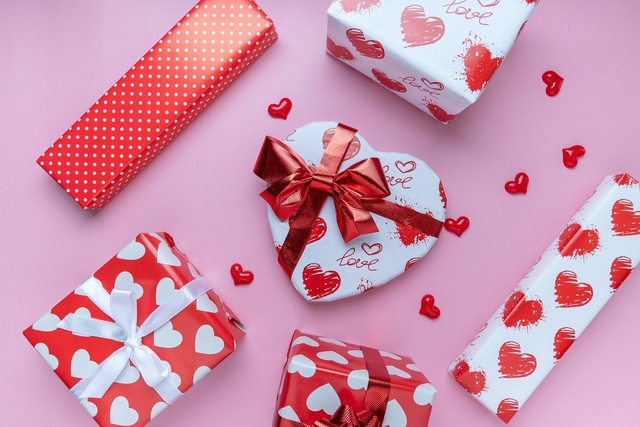 gifts wrapped in heart-themed wrapping paper with valentine's day quotes for him