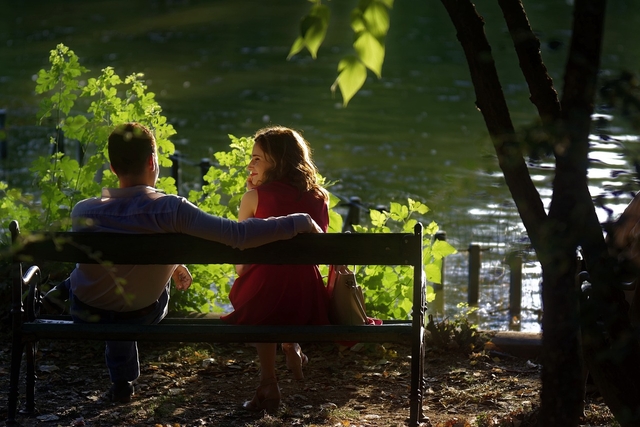 couple having their first date in a park asking good first date questions while seating and looking at a lake