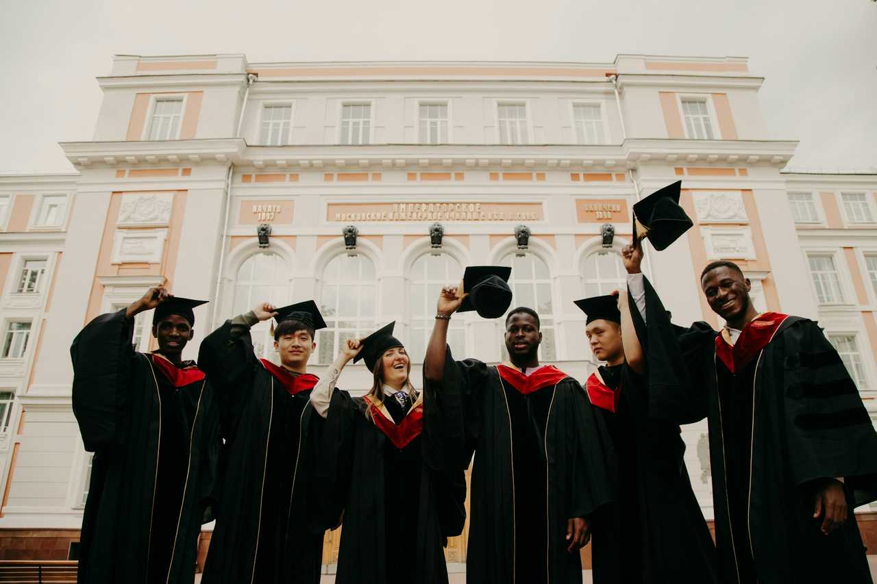 friends graduating and taking out their hats on graduation day