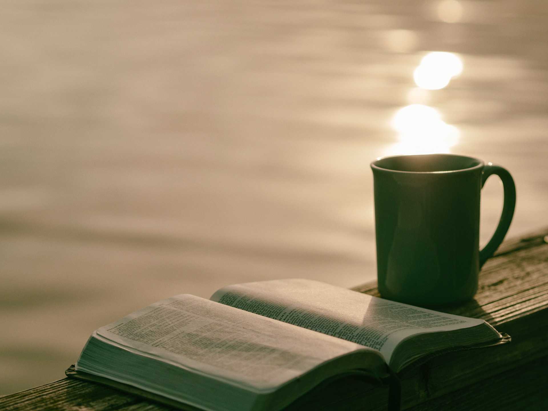 cup and open book close to a lake with good morning dad messages