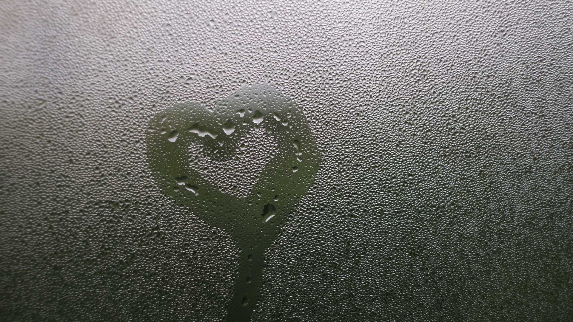 heart drawn in a wet glass surface as a miss you love message