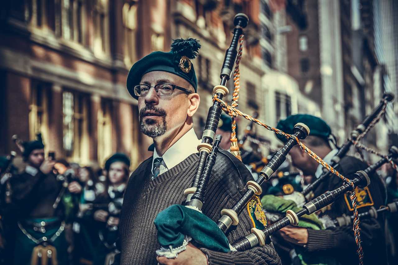 man carrying bagpipes and dressed thematically during a parade in st patrick's day