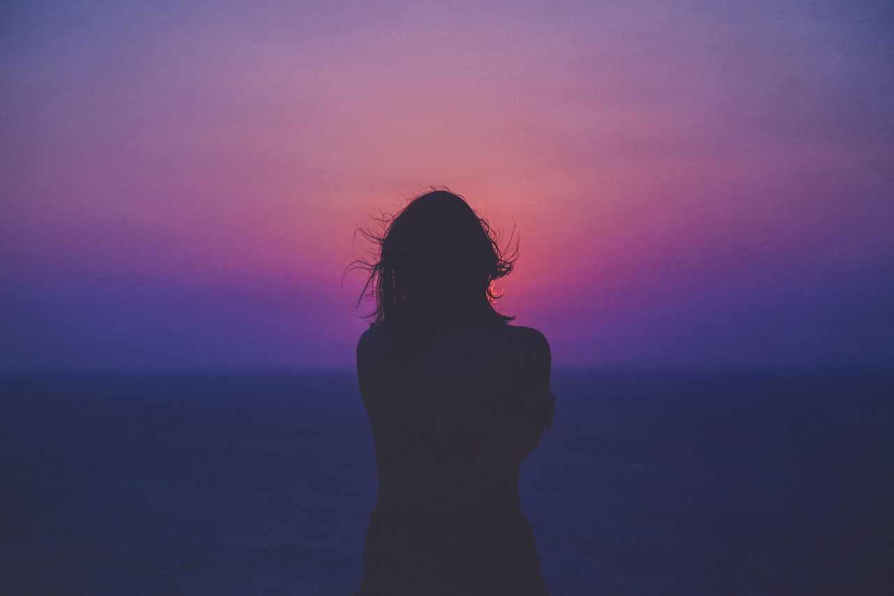 woman stading alone after receiving break up messages for girlfriend looking to the dusk horizon