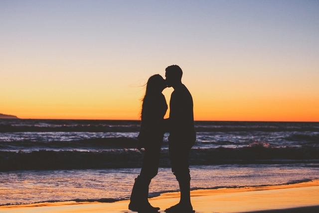 couple kissing at a first date, silhouette in the sunset at the beach