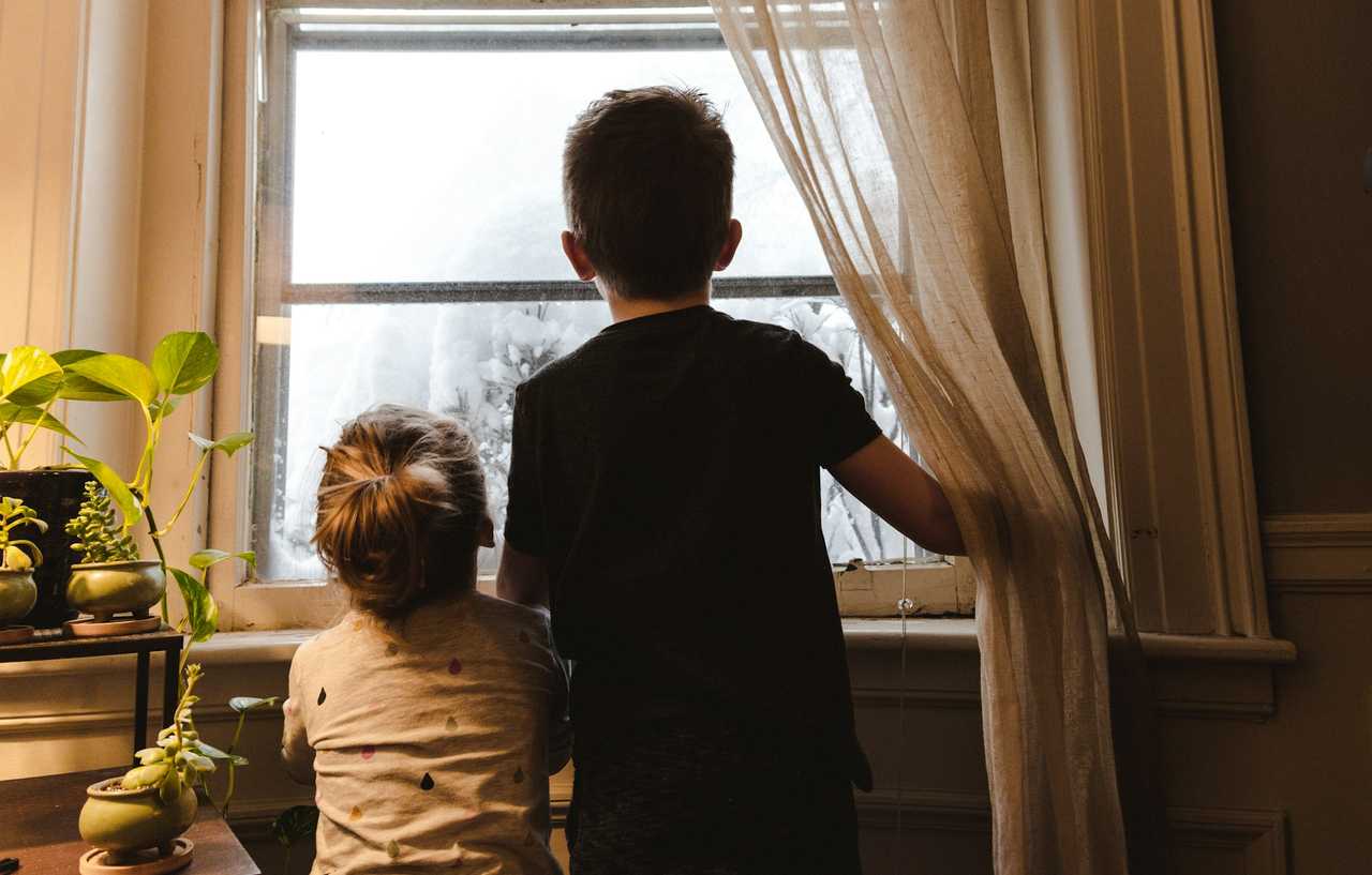 older and younger brother looking through a window on the younger's birthday