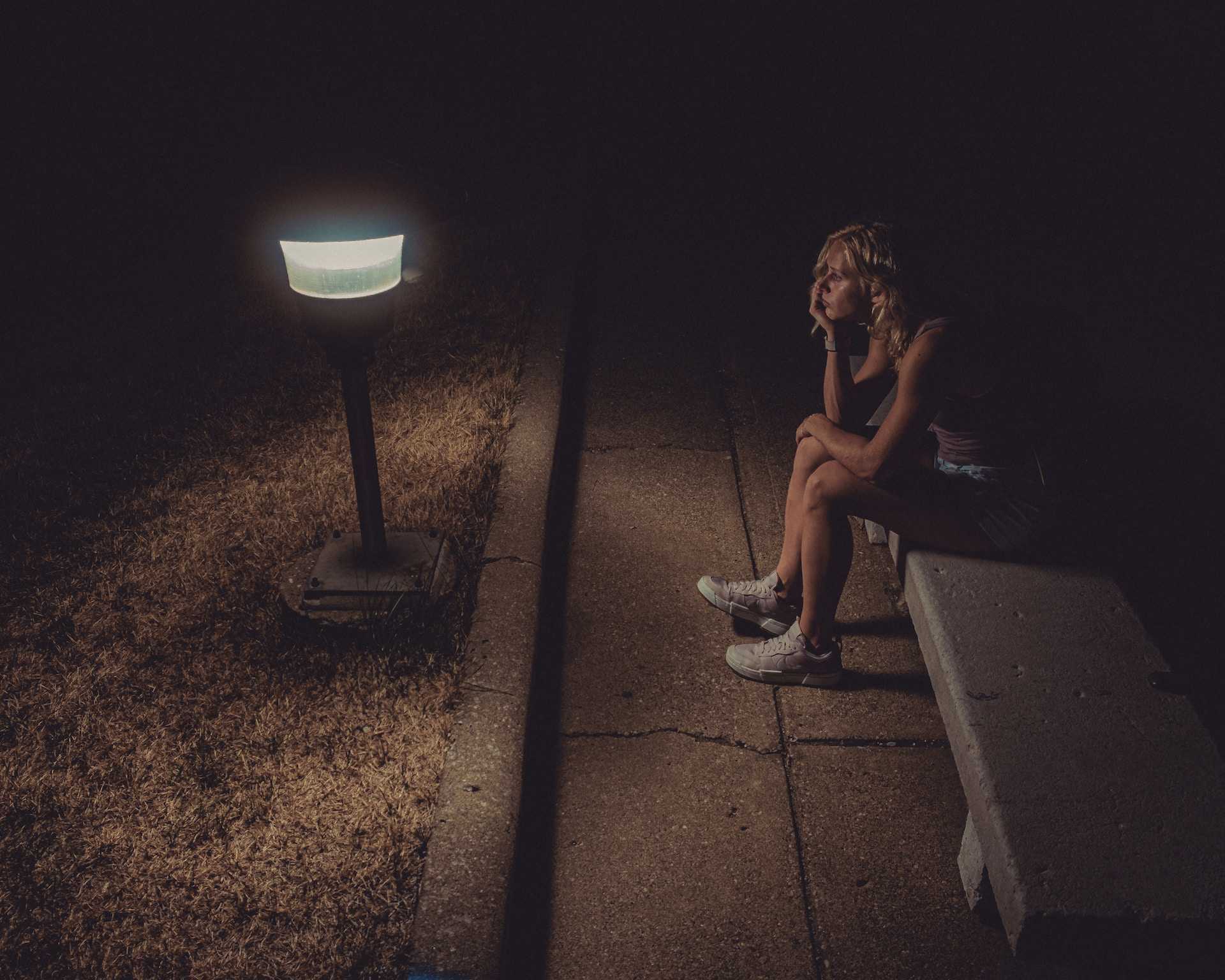 woman sitting in a bench alone at night after receiving break up messages