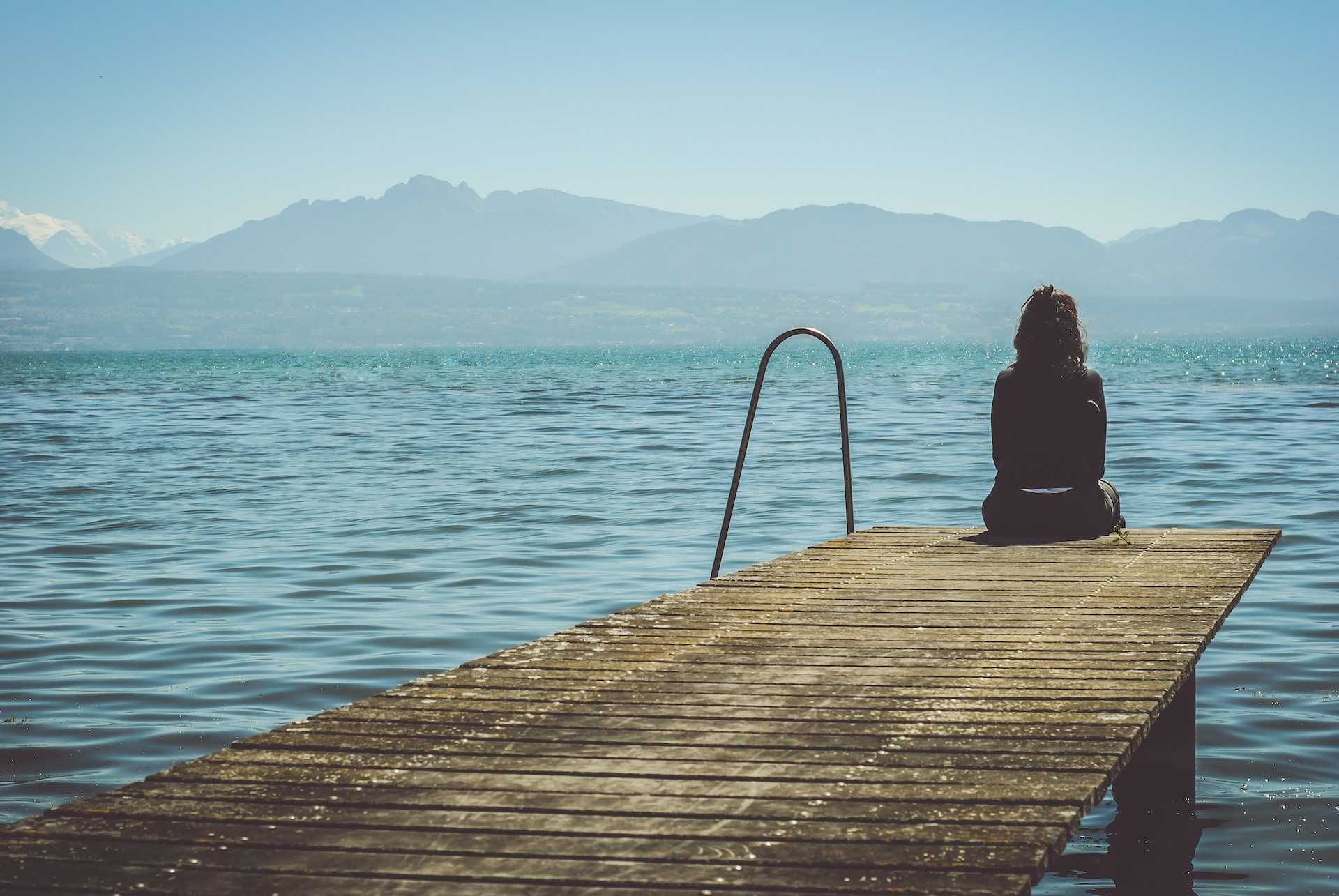 woman sitting in a dock by the sea sad because she ended a relationship with break up messages