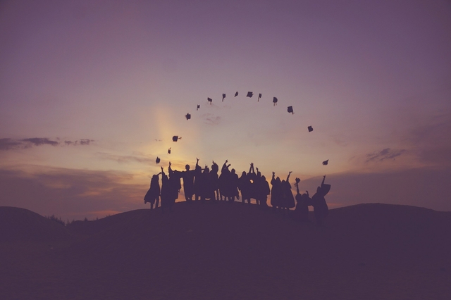 law graduates throwing their graduation hats forming an arch over the horizon in a sunset landscape