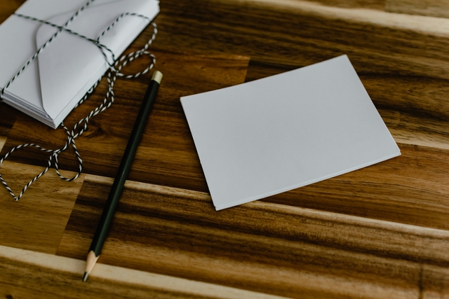 blank greeting card next to a pencil to write in the card over a wooden table